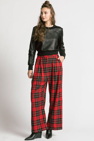 Model wearing red tartan pants with black faux leatherette Gone top by Allison Wonderland. 