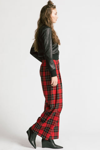 Side view of model wearing red tartan pants with black faux leatherette Gone top by Allison Wonderland. 