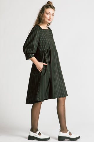 Side view of woman wearing black and white pinstripe relaxed babydoll Notebook dress by Allison Wonderland. 