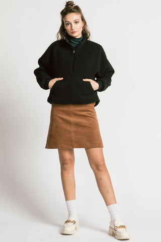 Woman wearing camel cord skirt with black half zip Sense pullover by Allison Wonderland. 