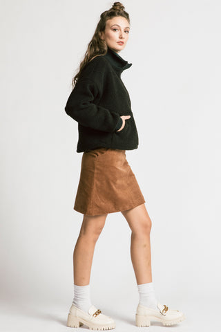 Side view of woman wearing camel cord skirt with black half zip Sense pullover by Allison Wonderland. 