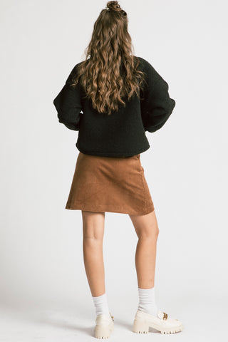 Back view of woman wearing camel cord skirt with black half zip Sense pullover by Allison Wonderland. 