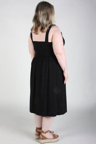 Back view of woman wearing black fit and flare Thornbill dress by Birds of North America. 