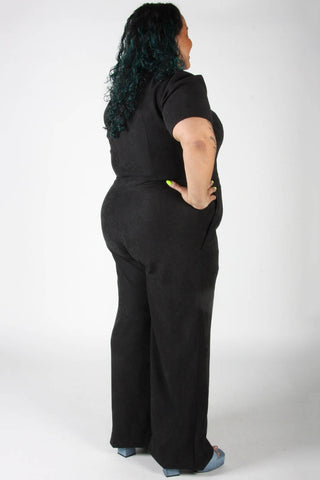 Back view of model wearing black zip up Tyrannulet jumpsuit by Birds of North America. 