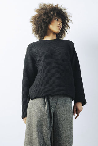 Model wearing tweed pants and black Deveron crewneck sweatshirt by Bodybag. 