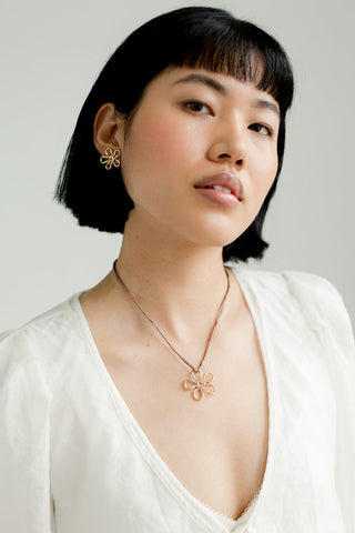 Woman wearing gold flora stud earrings by Kara Yoo. 