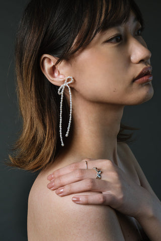 Woman wearing rice pearl and sterling silver Maya bow earrings by Kara Yoo. 