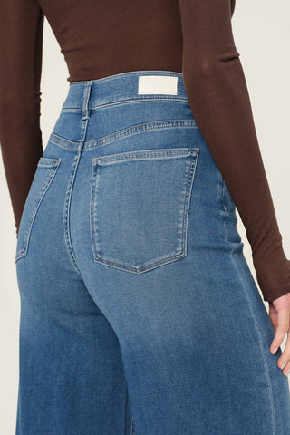 Back close-up view of woman wearing brown shirt and DL1961 Hepburn Wide Leg jeans in Mohong wash. 