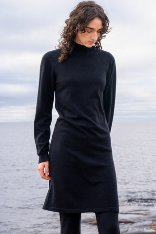 Woman at water wearing black merino wool sweater dress by Dinadi. 