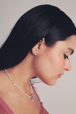 Woman wearing silver Kara Yoo Estelle star shaped stud earrings. 