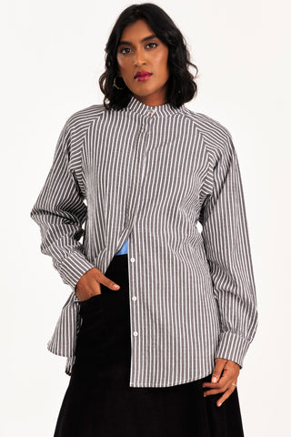 Woman wearing an oversized grey and white seersucker stripe button up Adore shirt by Jennifer Glasgow. 