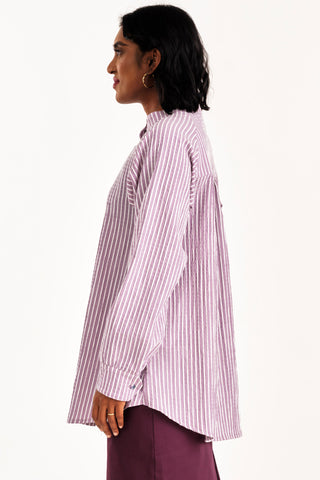 Side view of woman wearing an oversized grey and white seersucker stripe button up Adore shirt by Jennifer Glasgow. 