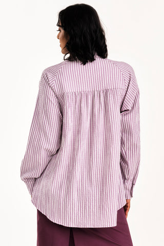 Back view of woman wearing an oversized grey and white seersucker stripe button up Adore shirt by Jennifer Glasgow. 