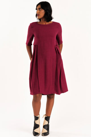 Woman wearing knee length burgundy Boudica dress by Jennifer Glasgow. 