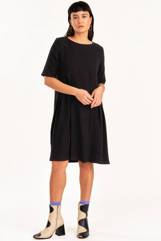 Woman wearing black knee length short sleeve Boudica dress by Jennifer Glasgow. 