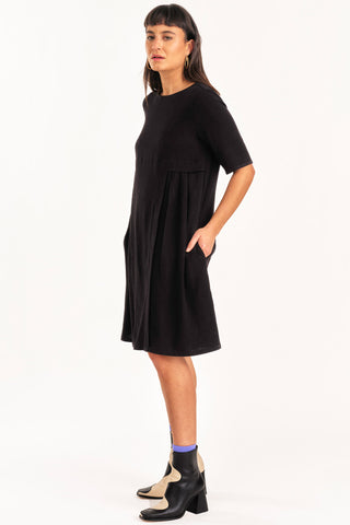 Side view of woman wearing black knee length short sleeve Boudica dress by Jennifer Glasgow.