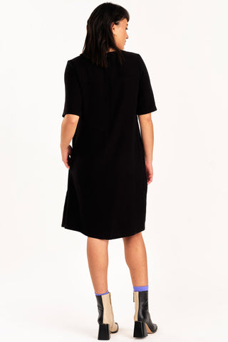 Back view of woman wearing black knee length short sleeve Boudica dress by Jennifer Glasgow.