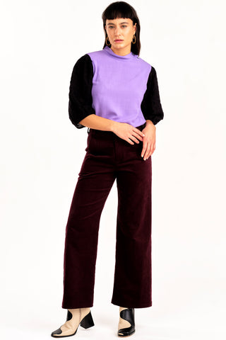 Woman wearing purple and black top with 70s inspired high waist burgundy fine corduroy Diana pant by Jennifer Glasgow. 