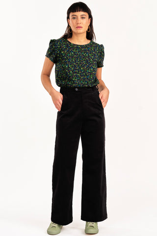 Woman wearing floral top with 70s inspired high waist black fine corduroy Diana pant by Jennifer Glasgow. 