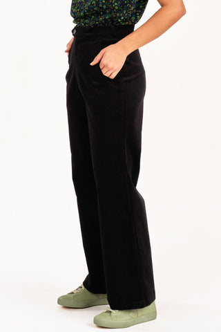 Side view of woman wearing floral top with 70s inspired high waist black fine corduroy Diana pant by Jennifer Glasgow. 