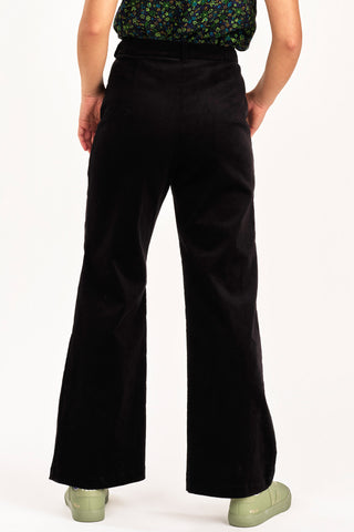 Back view of woman wearing floral top with 70s inspired high waist black fine corduroy Diana pant by Jennifer Glasgow. 