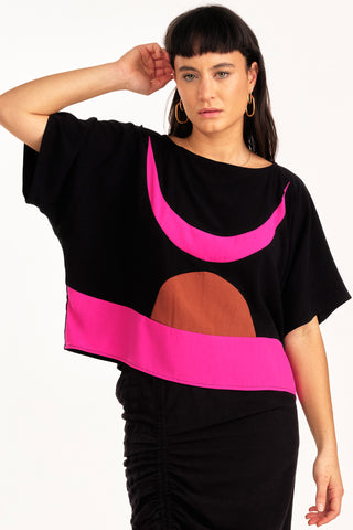 Woman wearing black and fuchsia colour blocked Embrace top by Jennifer Glasgow. 