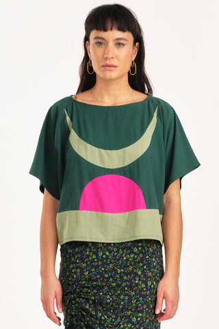 Woman wearing green and fuchsia colour blocked Embrace top by Jennifer Glasgow. 