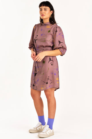 Woman wearing purple crop circle print button up Enduring Dress by Jennifer Glasgow. 