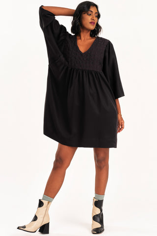 Woman wearing black loose fitting empire waist Exalt dress by Jennifer Glasgow. 