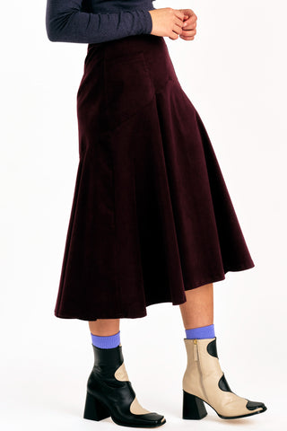 Side view of woman wearing grey mock neck shirt and burgundy fine corduroy flared Fjord skirt by Jennifer Glasgow. 