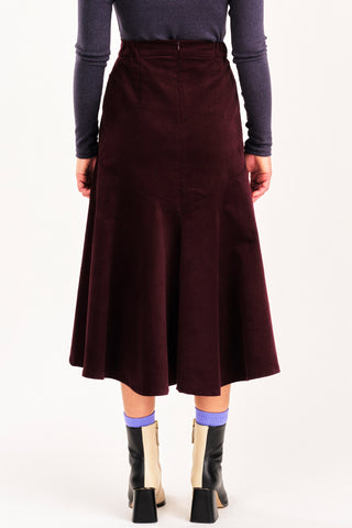 Back view of woman wearing grey mock neck shirt and burgundy fine corduroy flared Fjord skirt by Jennifer Glasgow. 