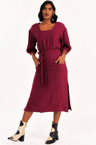 Woman dress wearing burgundy midi length Grace dress by Jennifer Glasgow. 