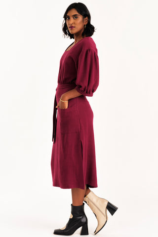 Side view of woman dress wearing burgundy midi length Grace dress by Jennifer Glasgow. 