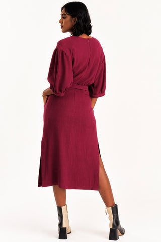 Back view of woman dress wearing burgundy midi length Grace dress by Jennifer Glasgow. 