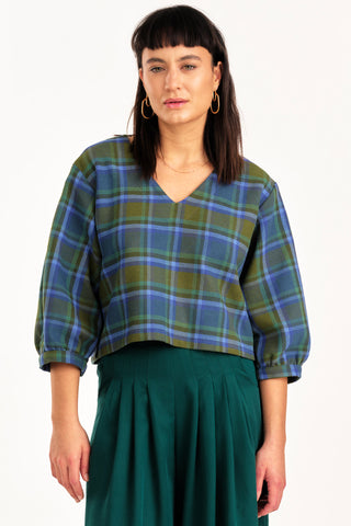 Woman wearing green and blue tone plaid v-neck Love top by Jennifer Glasgow. 