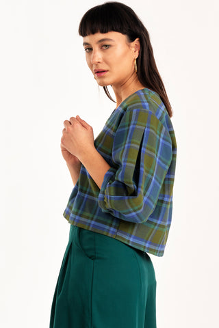 Side view of woman wearing green and blue tone plaid v-neck Love top by Jennifer Glasgow. 