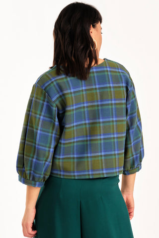 Back view of woman wearing green and blue tone plaid v-neck Love top by Jennifer Glasgow. 