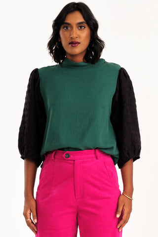 Woman wearing green and black mock neck Solace top by Jennifer Glasgow. 