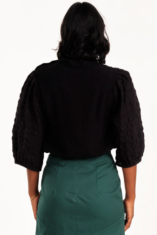 Back view of woman wearing black mock neck Solace top by Jennifer Glasgow. 