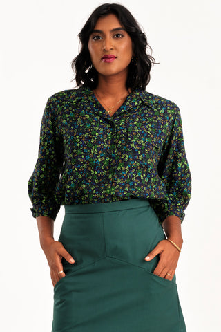 Woman wearing black and green floral print button up Treasure blouse by Jennifer Glasgow. 