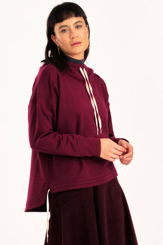 Woman wearing burgundy hooded Valentia sweater by Jennifer Glasgow. 