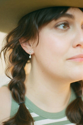 Woman wearing silver and pearl Daisy Pearl earrings by Manufacture Fait Main. 