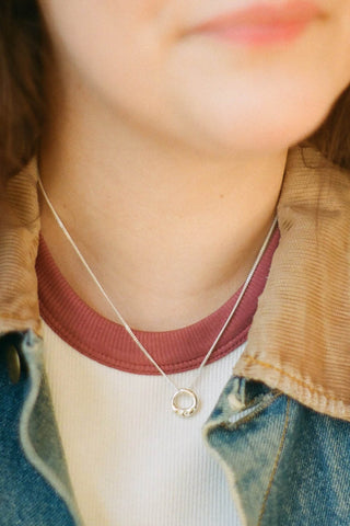 Woman wearing sterling silver Ombrelle pendant necklace by La Manufactured Fait Main.