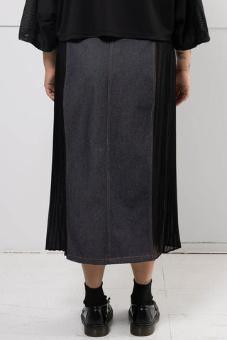 Back view of model wearing black denim Harmony skirt with pleated chiffon side panels by Mercy House. 