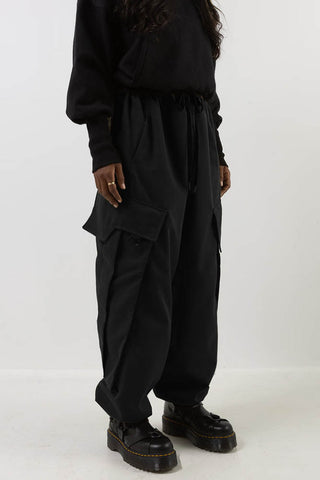 Model wearing black cotton twill Jiyu cargo pants by Mercy House. 