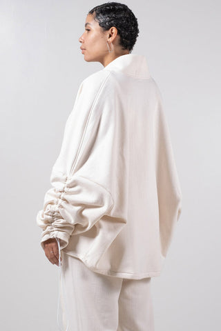 Back view of model wearing white open front Sylas Cardigan by Mercy House. 