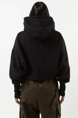 Back view of model wearing black Telfar hoodie by Mercy House. 