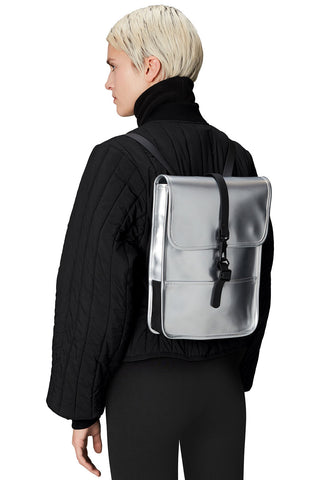 Model wearing silver mirror Backpack Micro W3 by RAINS. 