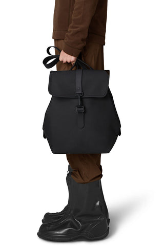 Model holding black Bucket Backpack W3 by RAINS. 