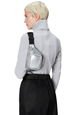 Woman wearing silver RAINS Bum Bag Micro across her shoulder. 